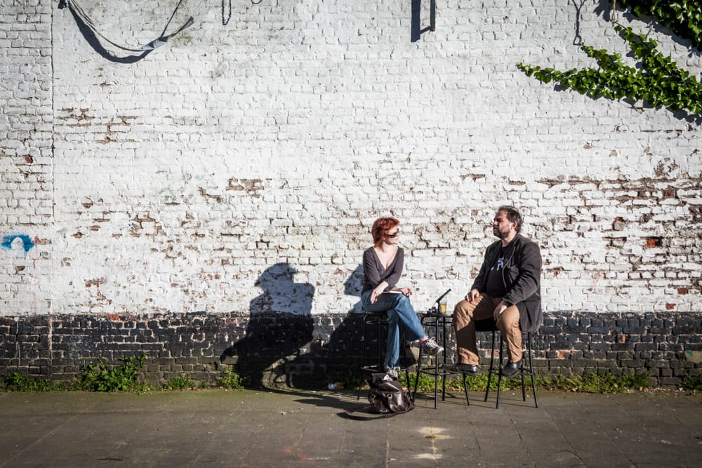Dans la cour de l'Os à Moelle, Daniel Hélin est interviewé par Clotilde Delcommune. ils sont sur des tabourets de bar. C'est incongru, mais sympathique!