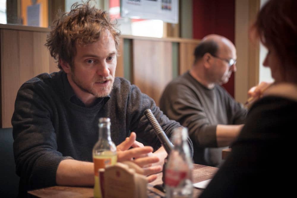 Valéry Rosier, les mains en éventail sur une table en bois, a l'air de très très fort réfléchir pour voir comment expliquer un truc. Tellement que ça a tout ébouriffé ses cheveux!