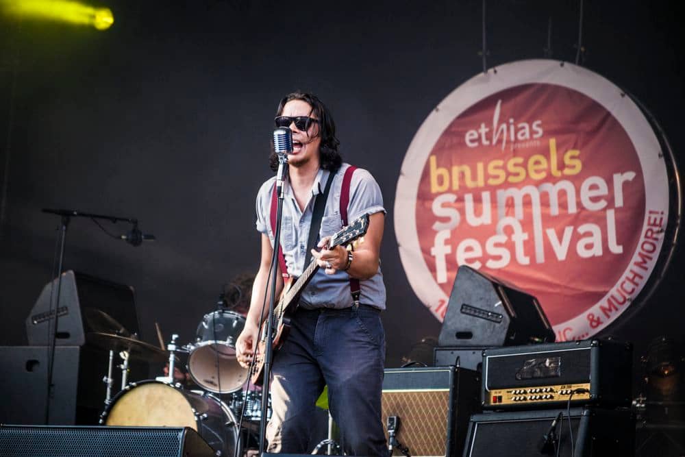 Lors de son concert au Brussels Summer Festival, Madé J joue de la guitare et crie dans le micro.