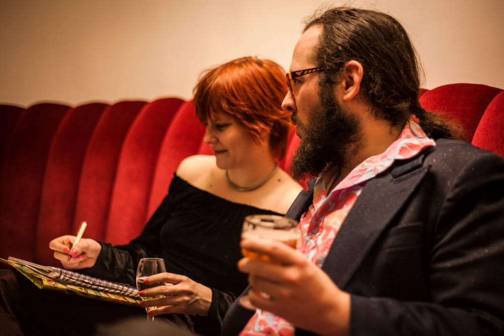 Nicolas Monfort et Clotilde Delcommune ont chacun un verre à la main. Il dit des trucs. Elle note.