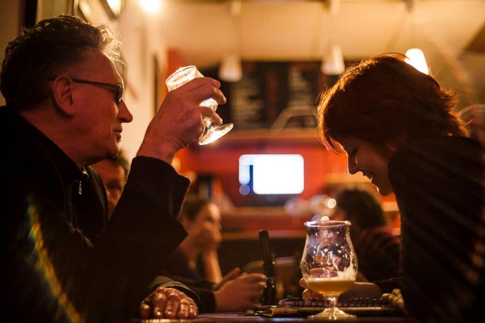 Dans un bar, un halo de lumière tombe sur Benoît Delépine et Clotilde Delcommune en plein interview.