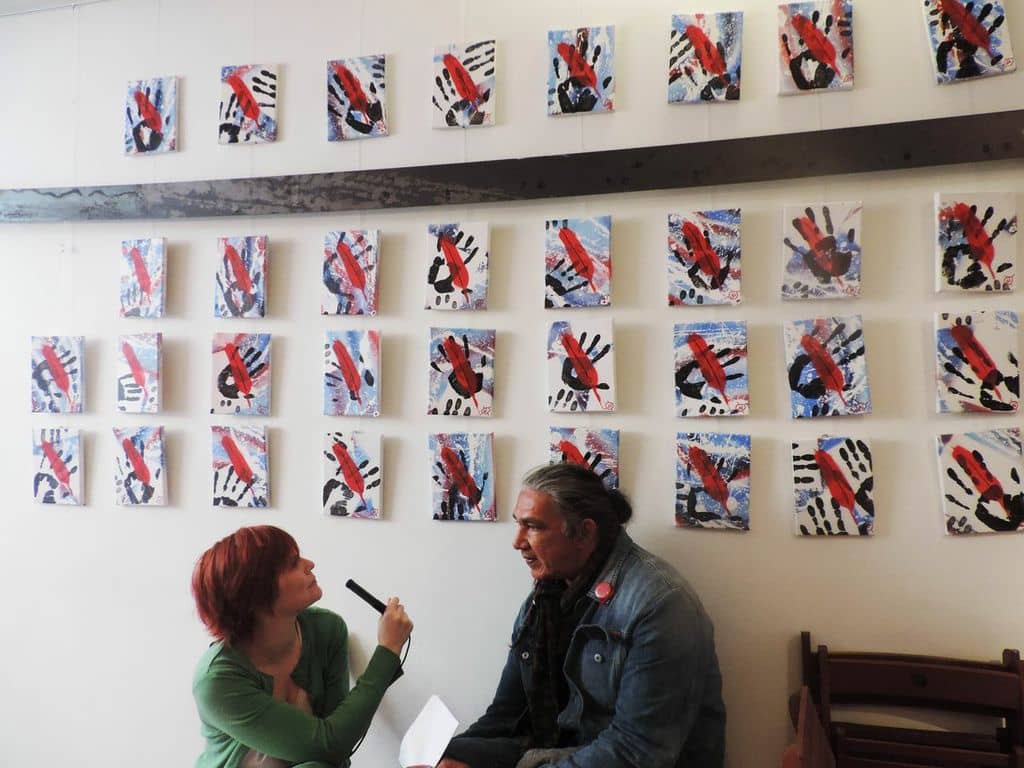 Clotilde Delcommune regarde les œuvres au mur lors de l'interview de Jacques Néwashish au Fiestival.