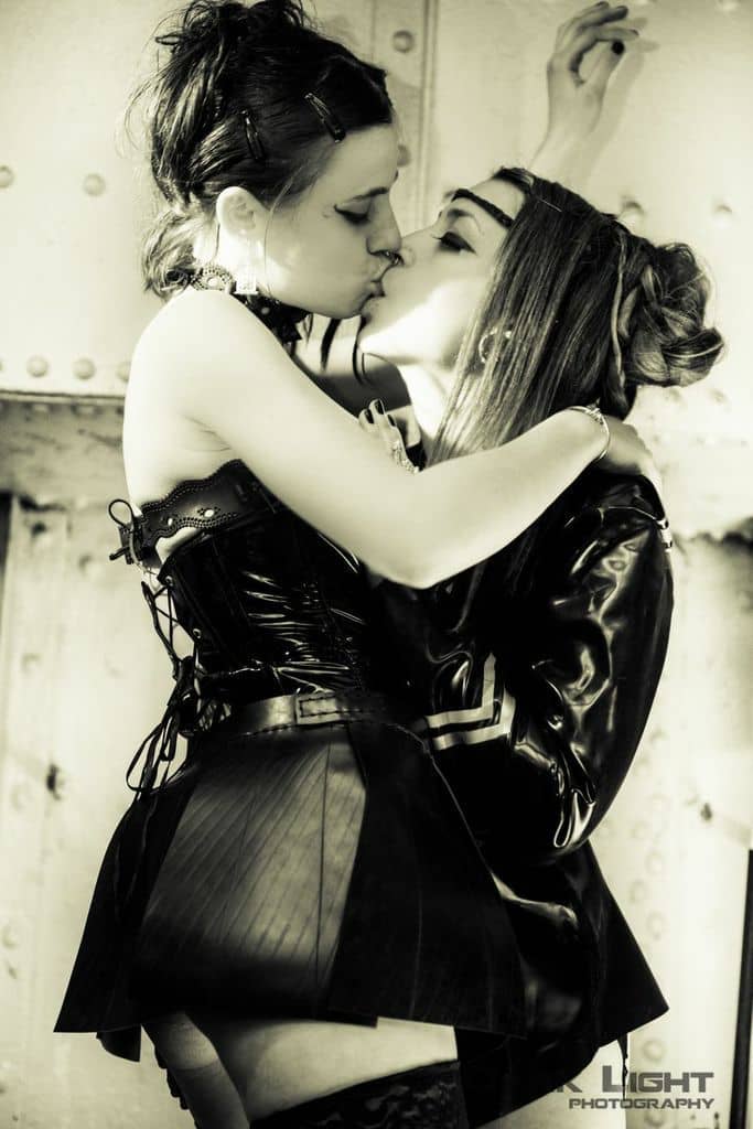 Deux femmes en petites tenues de latex s'embrassent à bouche-que-veux-tu.